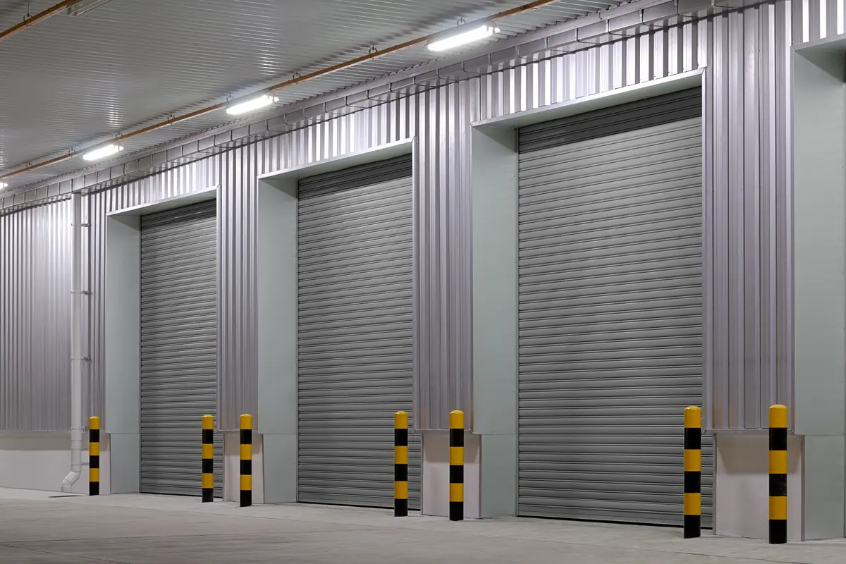 Row of closed steel-grey commercial roll-up security shutters on a warehouse loading bay